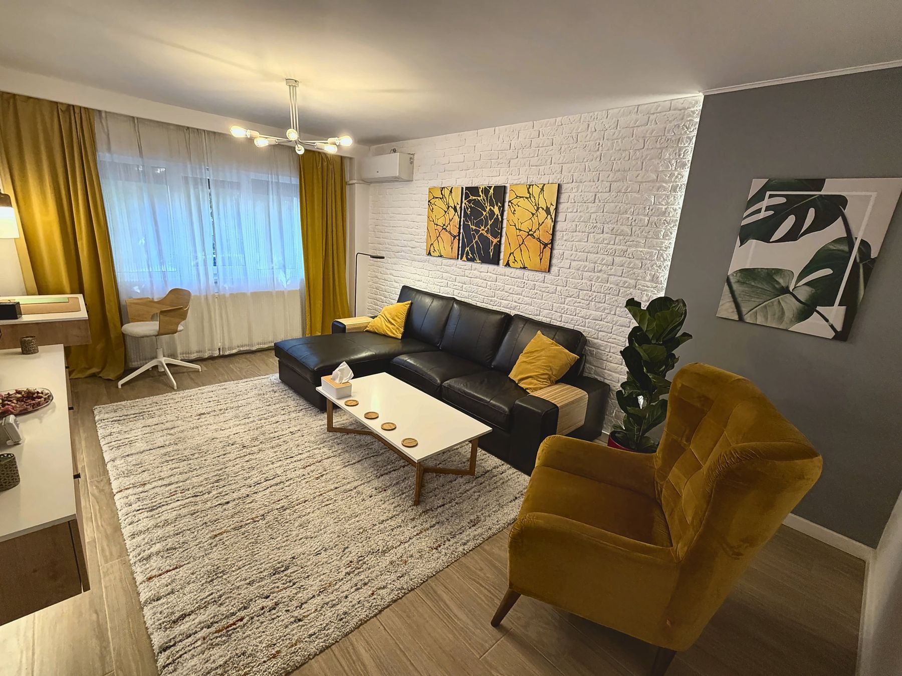 The living room, with sofa, yellow armchair and white brick wall